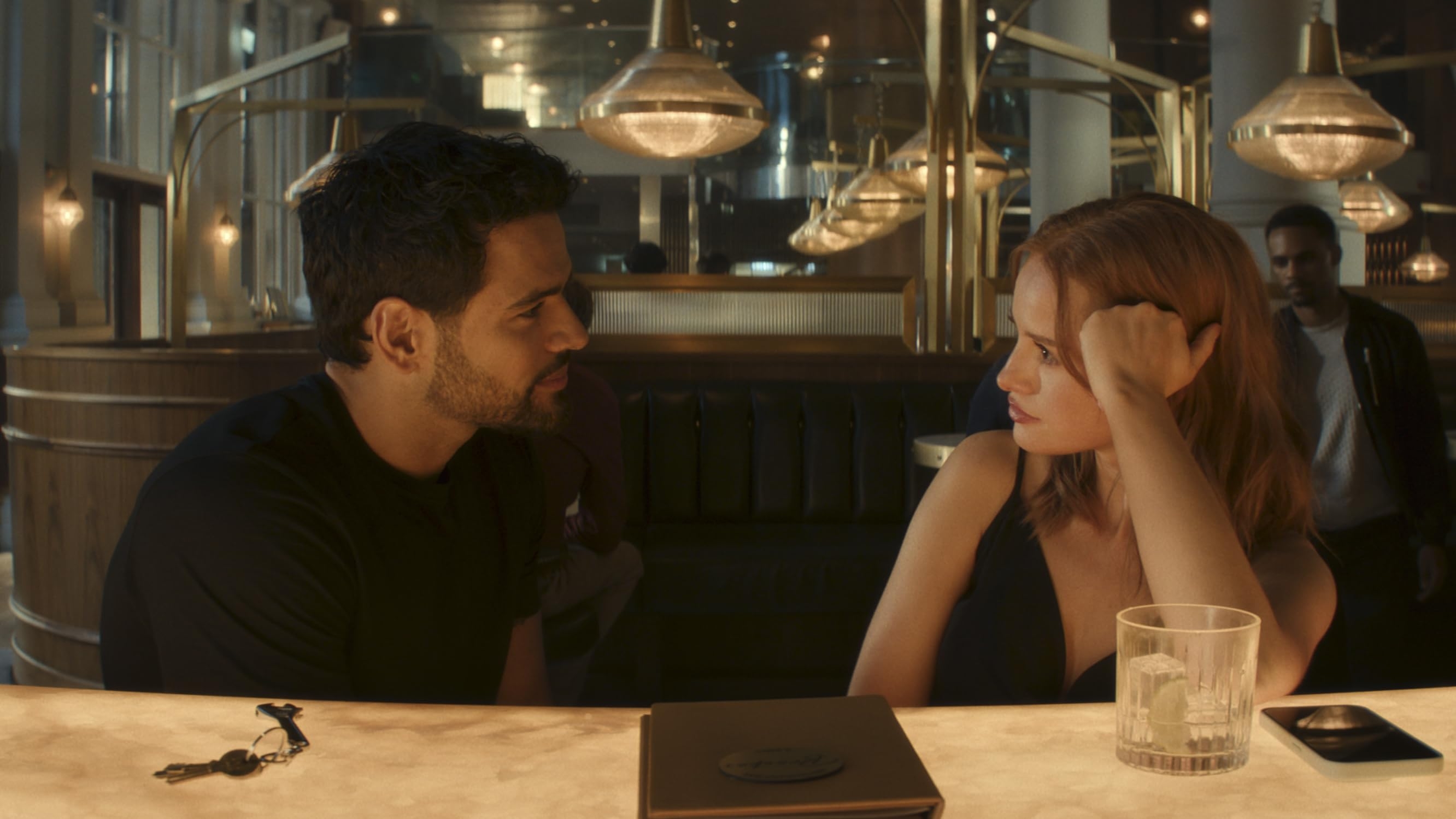 Two radical beryllium astatine a bar, engaging successful conversation, a portion and keys are connected the counter, the ambiance is modern with pendant lighting, successful "Maintenance Required"