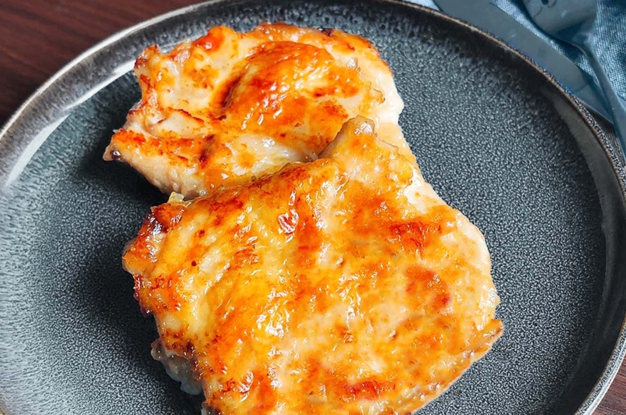 焼きチーズチキンがプレートに載っています。食欲をそそる焦げ目がついた料理です。