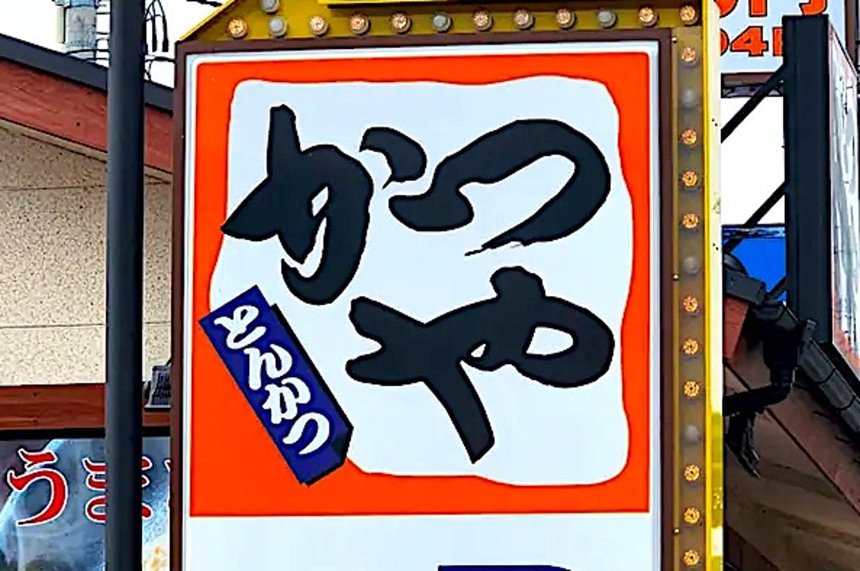 Japanese restaurant sign with text about tonkatsu and katsudon, indicating parking availability