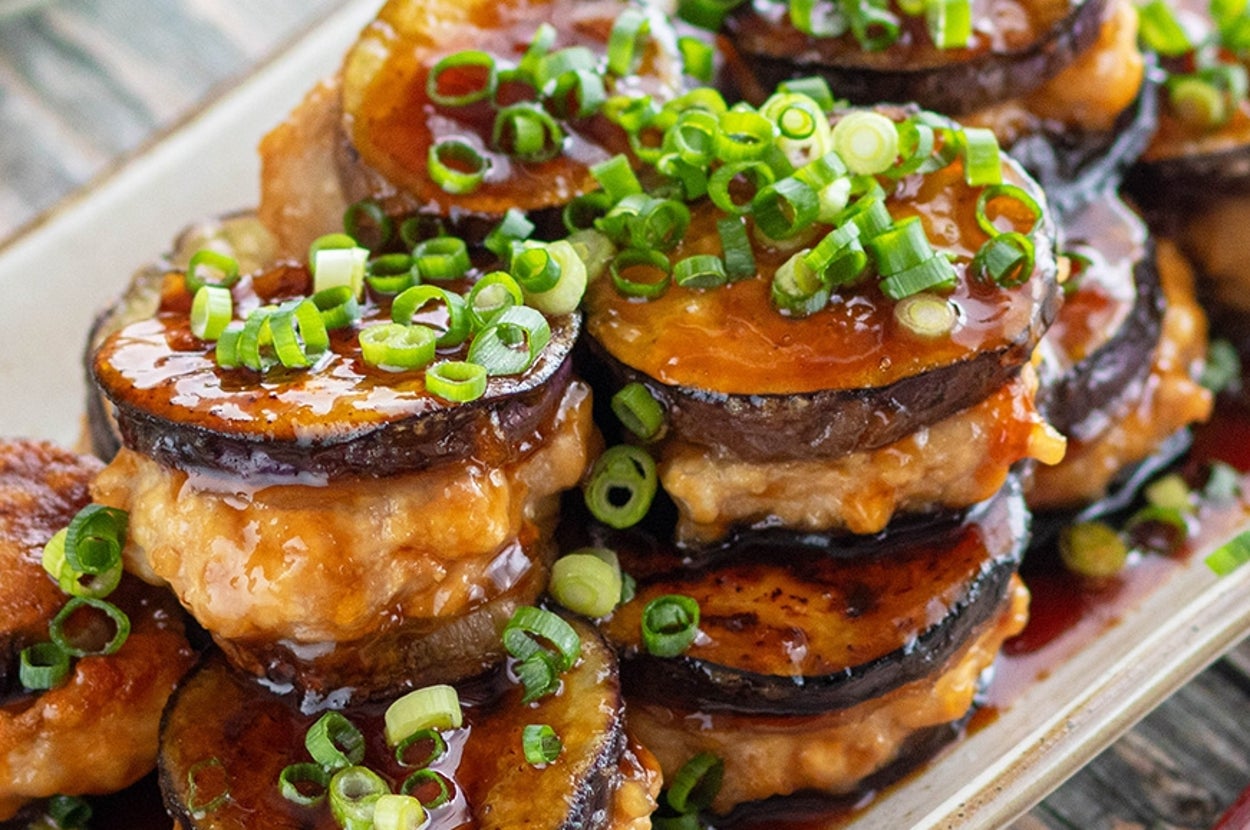ナスとひき肉の挟み焼きがタレで彩られ、ネギが散らされた料理。
