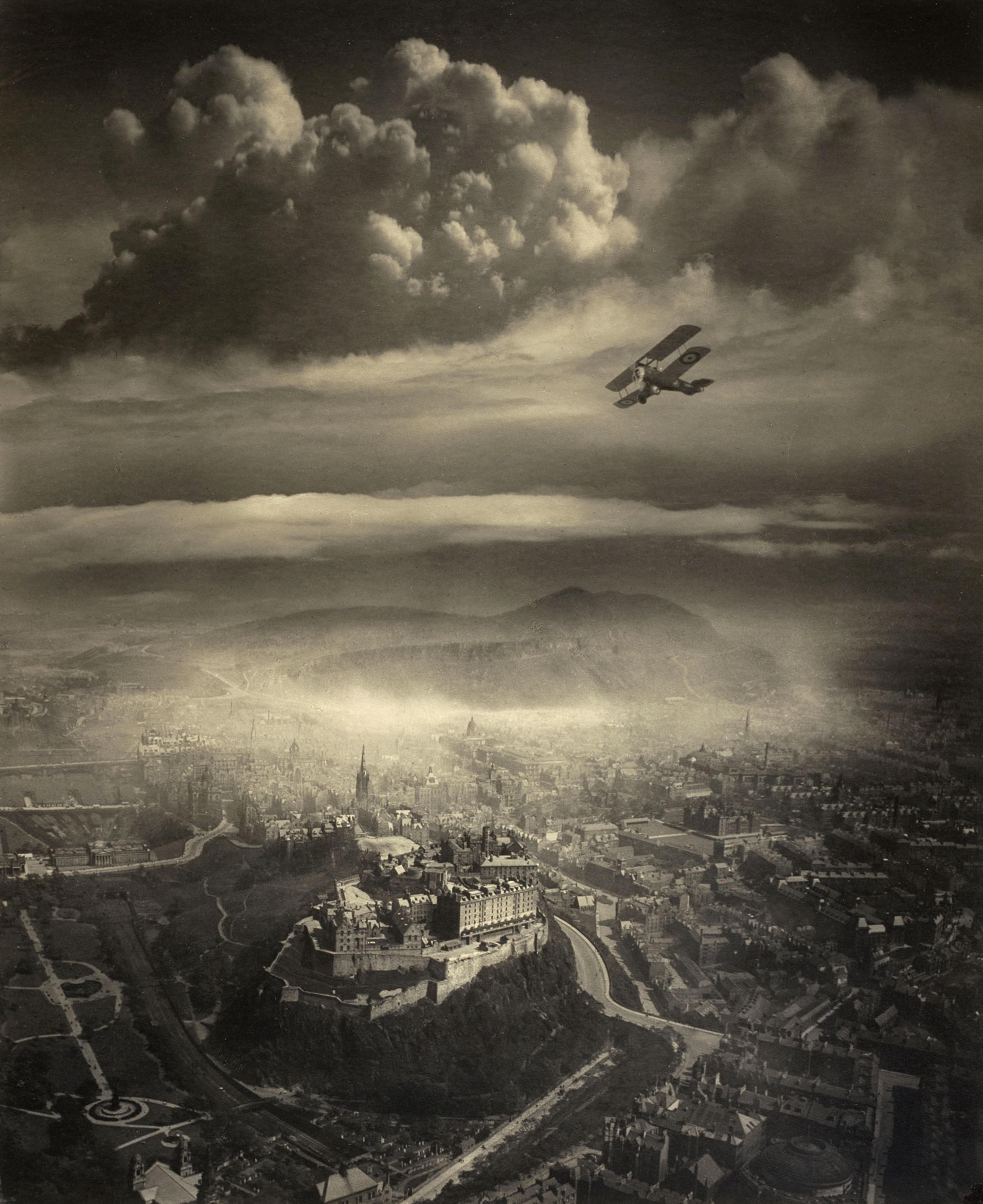 Biplane flying over a historical cityscape with a prominent castle, under dramatic cloud-filled skies