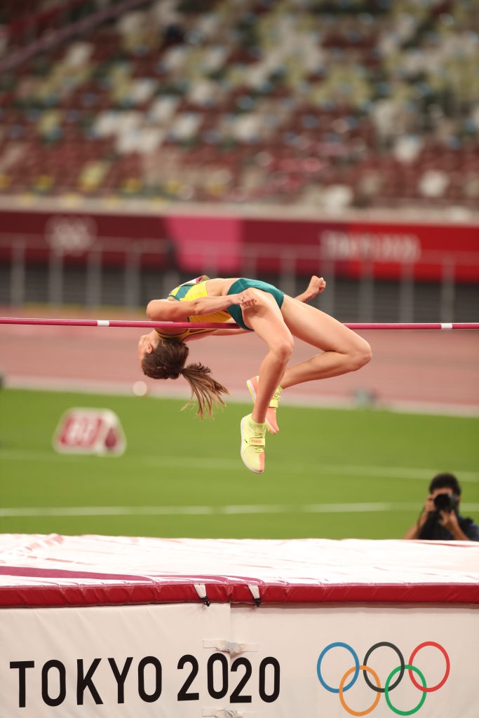Athlete performing a high jump at the Tokyo 2020 Olympics, clearing the bar gracefully