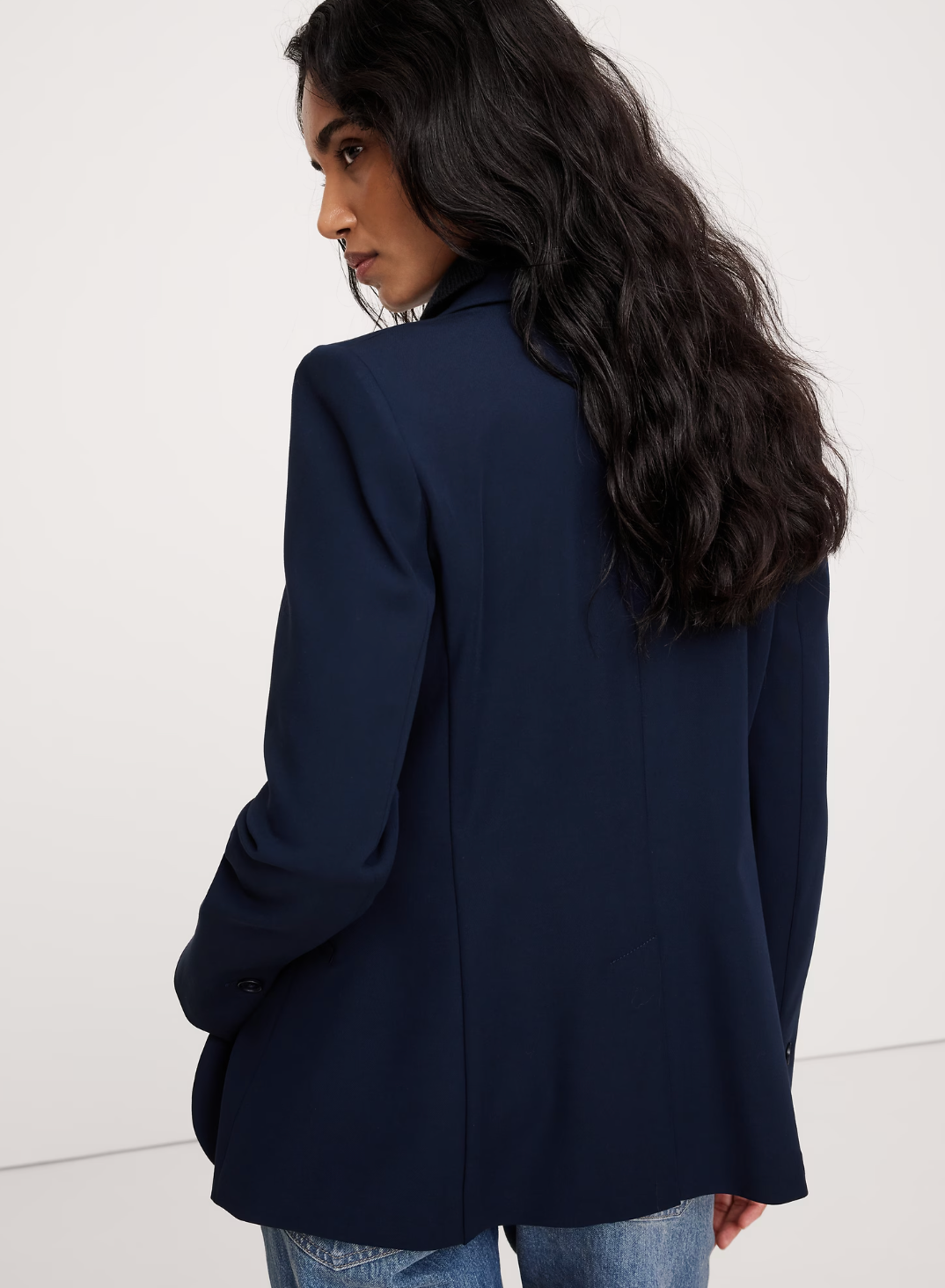 Person successful  a tailored blazer and jeans, looking implicit    their shoulder