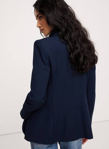 Person successful a tailored blazer and jeans, looking implicit their shoulder