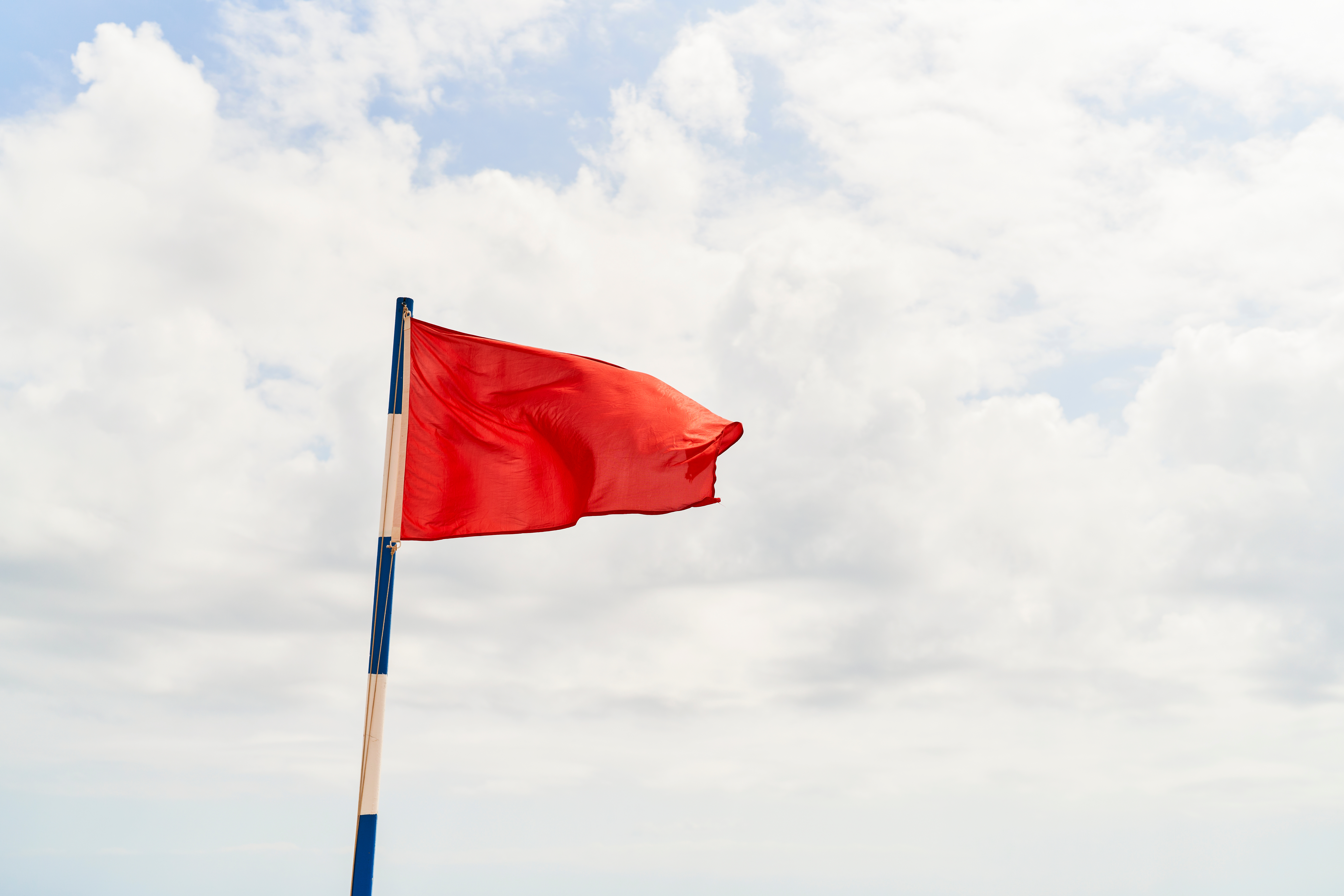 A reddish  emblem  waves connected  a formation  informing  rod  against a cloudy sky, indicating imaginable   information   oregon  hazardous conditions