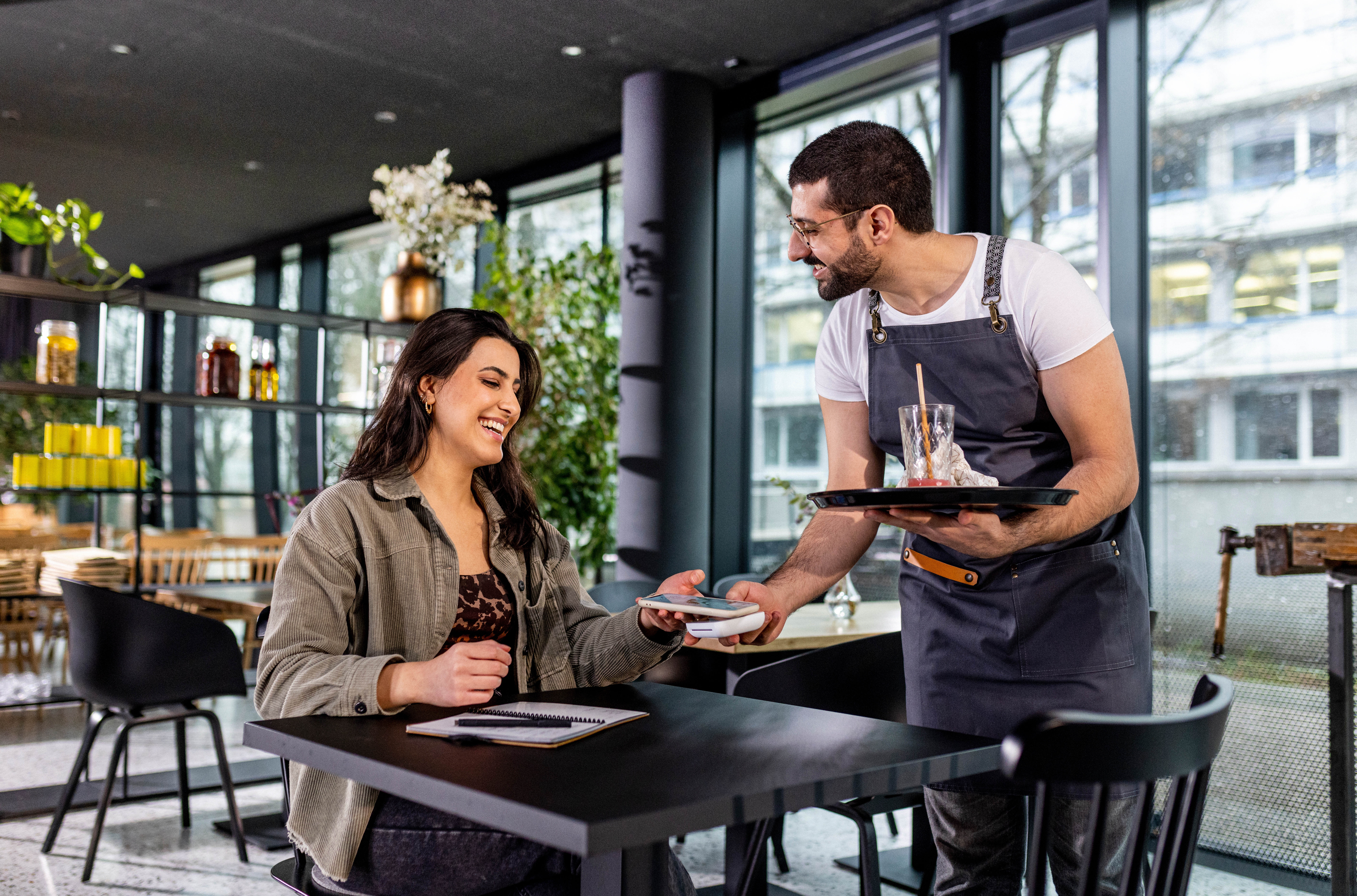 Server successful  apron hands cheque  to smiling pistillate   astatine  a café array  indoors