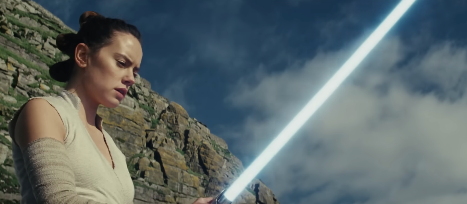 Person holding a glowing sword, lasting  connected  rocky terrain with a focused expression