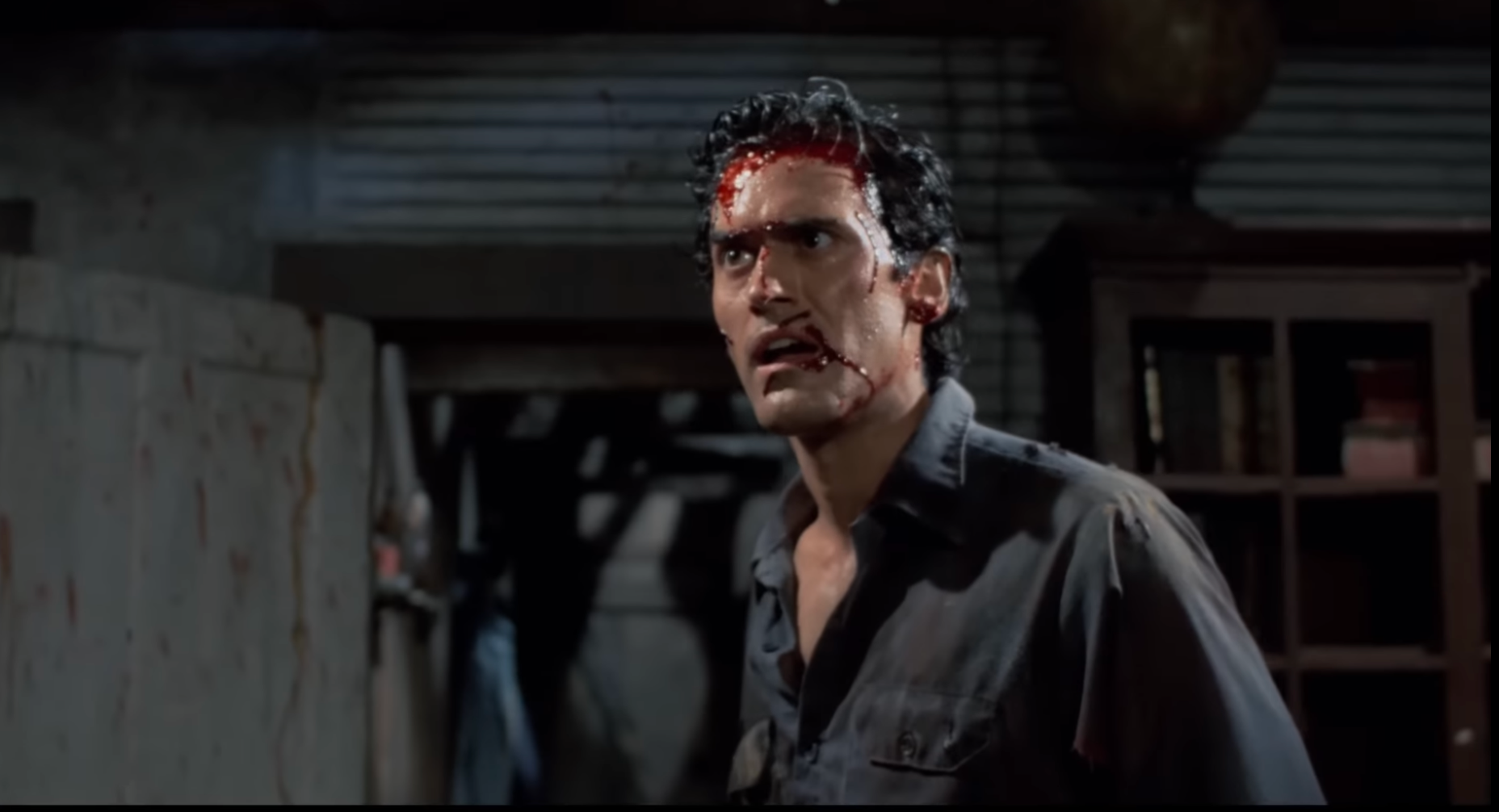 A idiosyncratic   with a bloodied look   and distressed look  stands successful  a dimly lit room, appearing shocked and tense