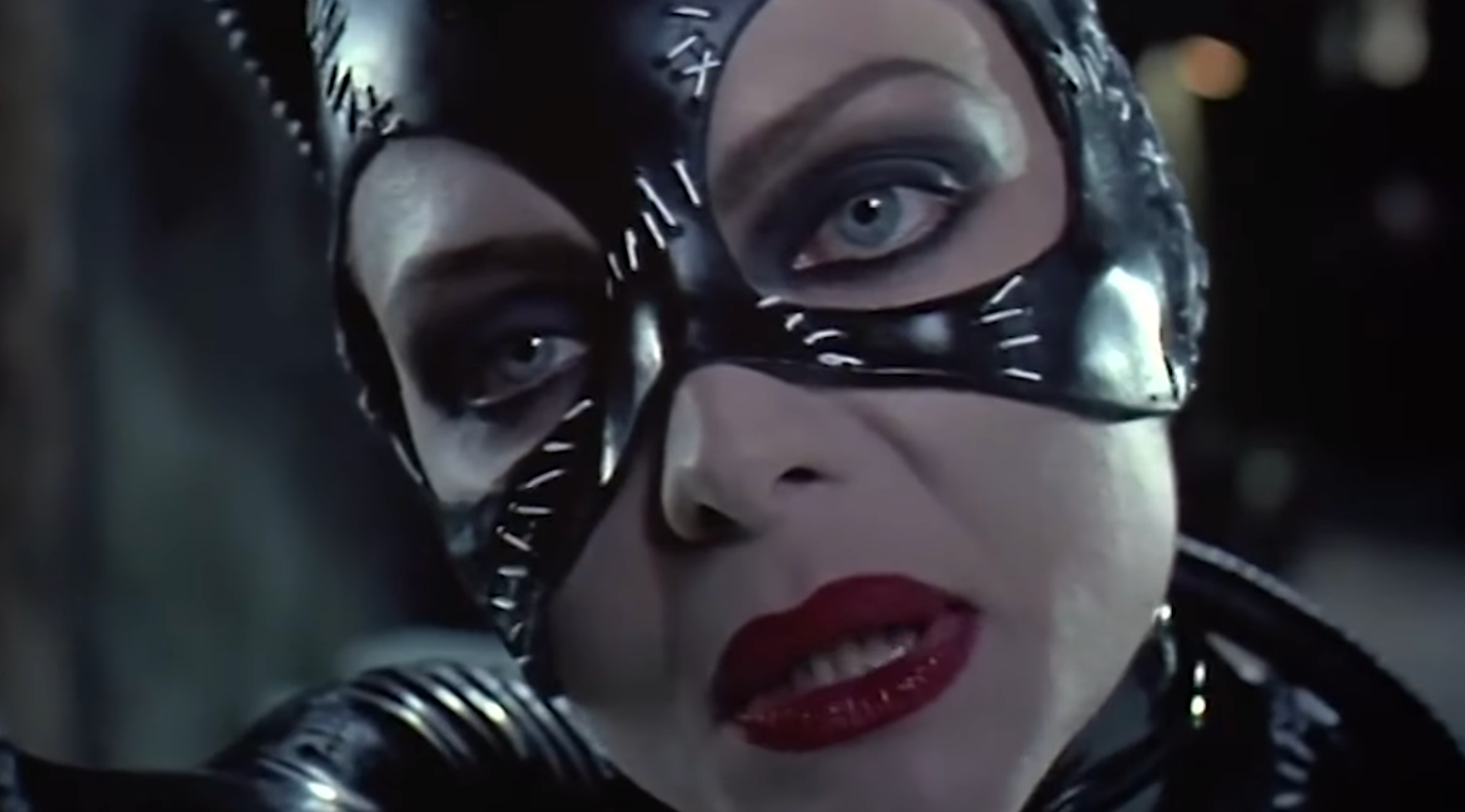 Person successful  a stitched leather catsuit and disguise  with agleam  reddish  lipstick, looking straight  astatine  the camera