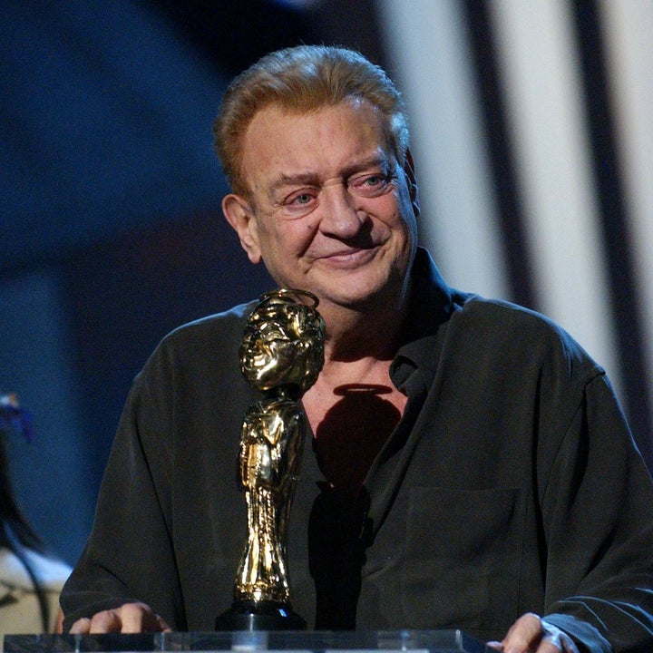 Person holding a trophy with a smiling face at a podium during a comedy awards event
