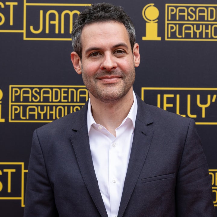 Person in a suit smiles in front of a backdrop featuring "Pasadena Playhouse" and "Jelly's Last Jam."