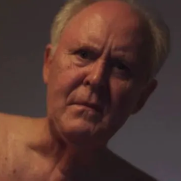 Elderly man looking intently, shirtless, with a serious expression