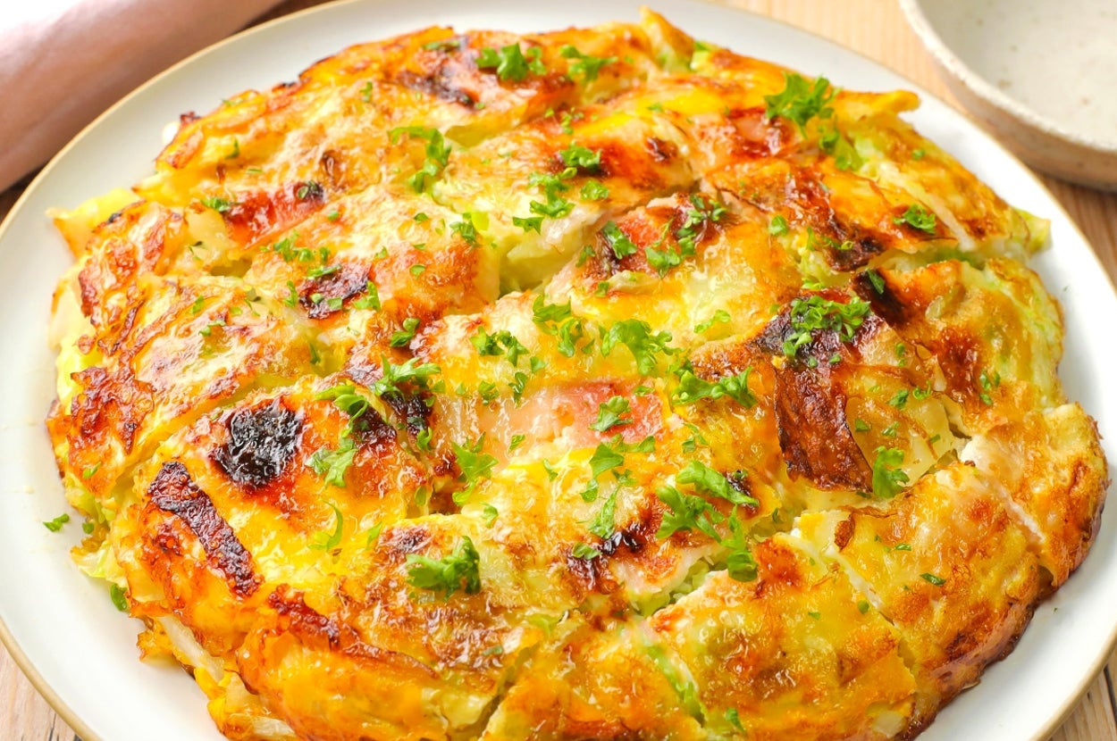 おいしそうな洋風オムレツが白い皿に盛られている。パセリが散りばめられている。