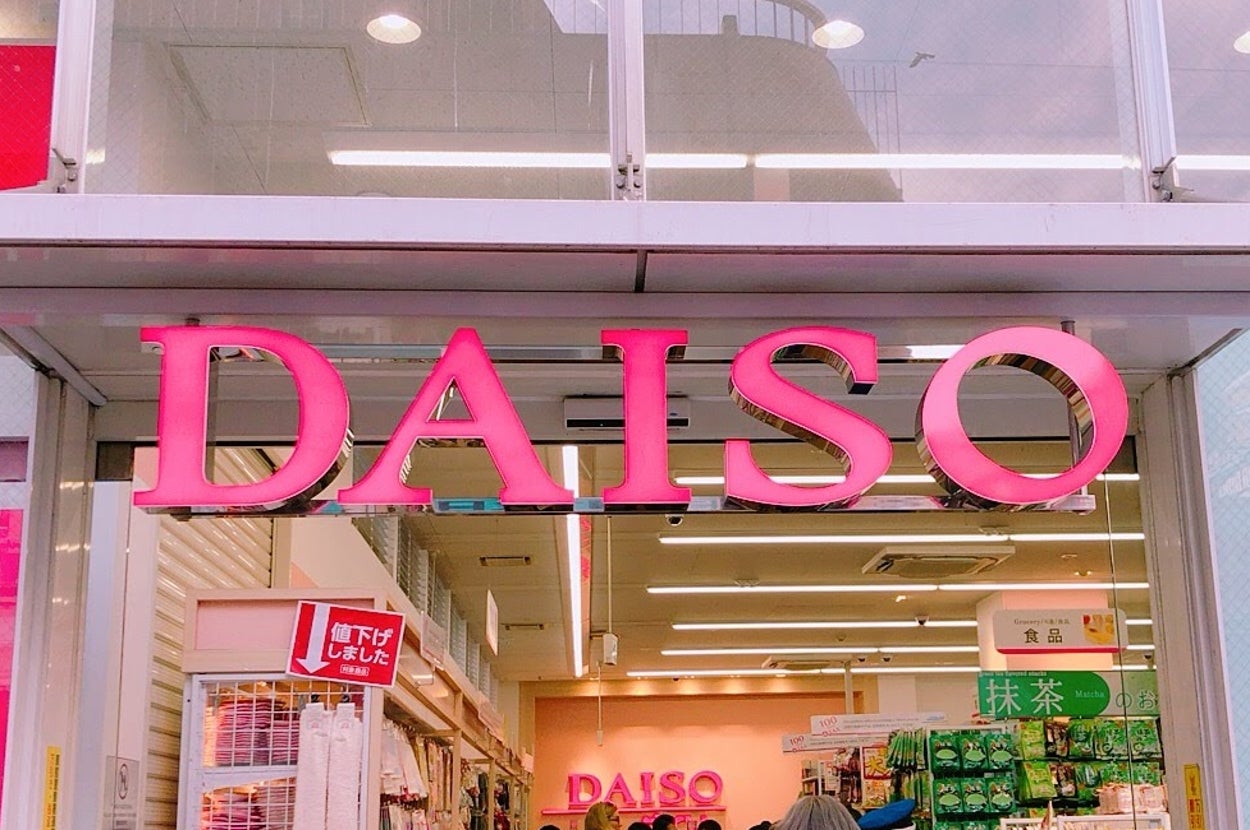 店「ダイソー」の入口。多くの人が出入りしている。店内には多様な商品が並べられている様子が見える。