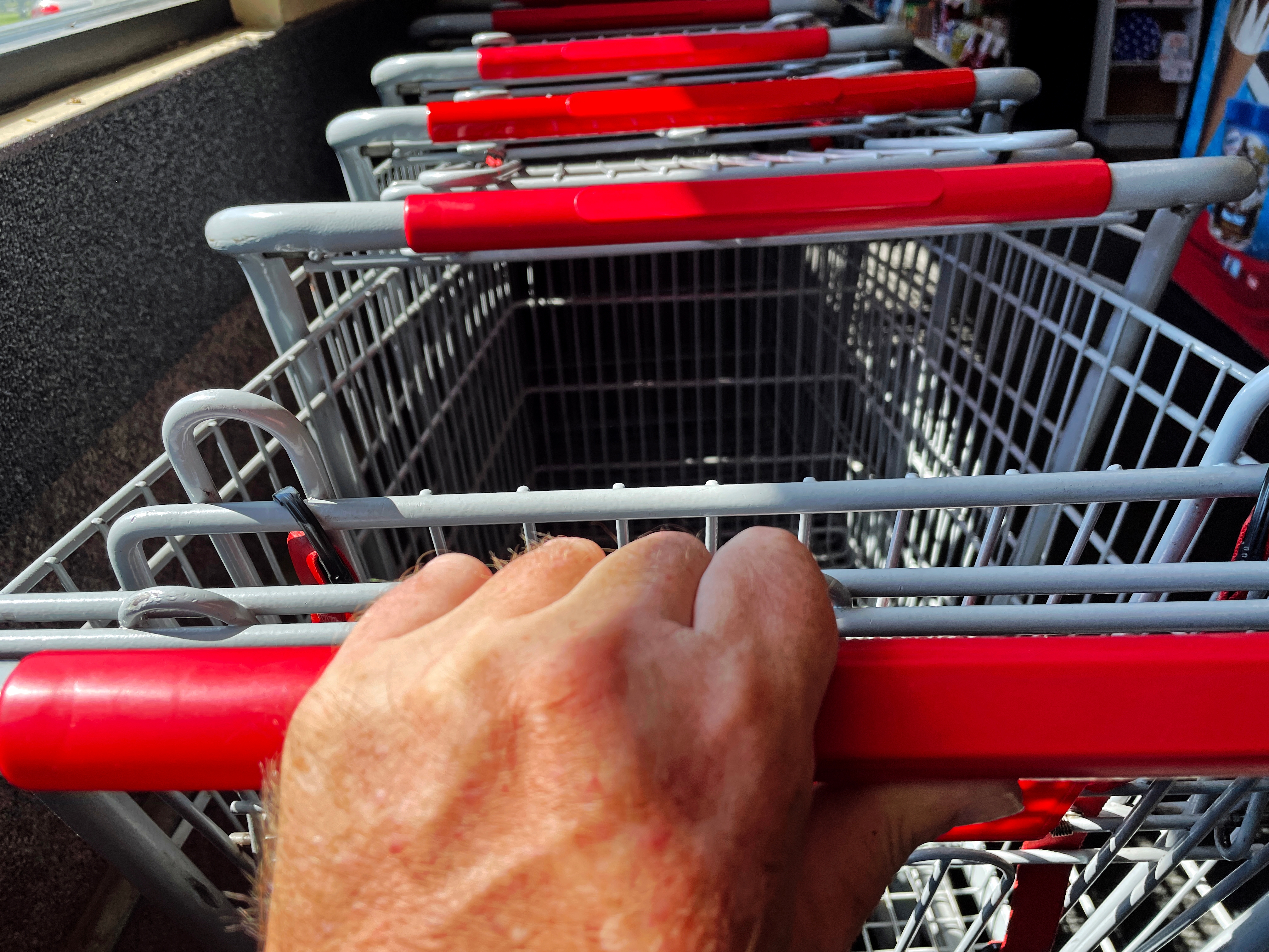 Hand holding a buying  cart grip  among a enactment      of carts extracurricular  a store   entrance