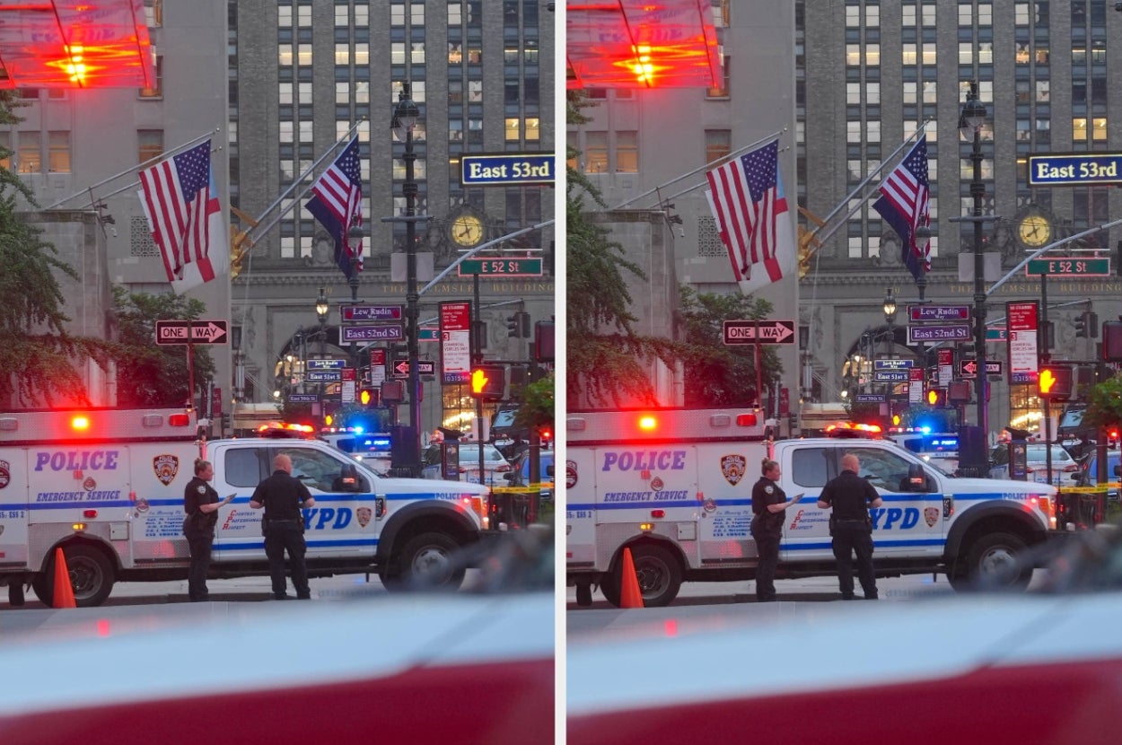 Police officers stand near an NYPD emergency vehicle on a city street, with American flags and city lights in the background