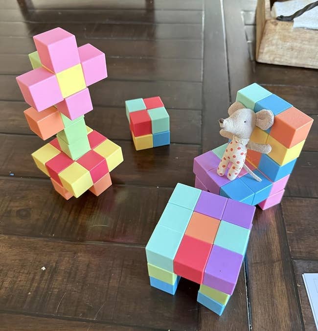 Toy blocks arranged into colorful seat and operation connected table; tiny cloth rodent artifact sits connected chair