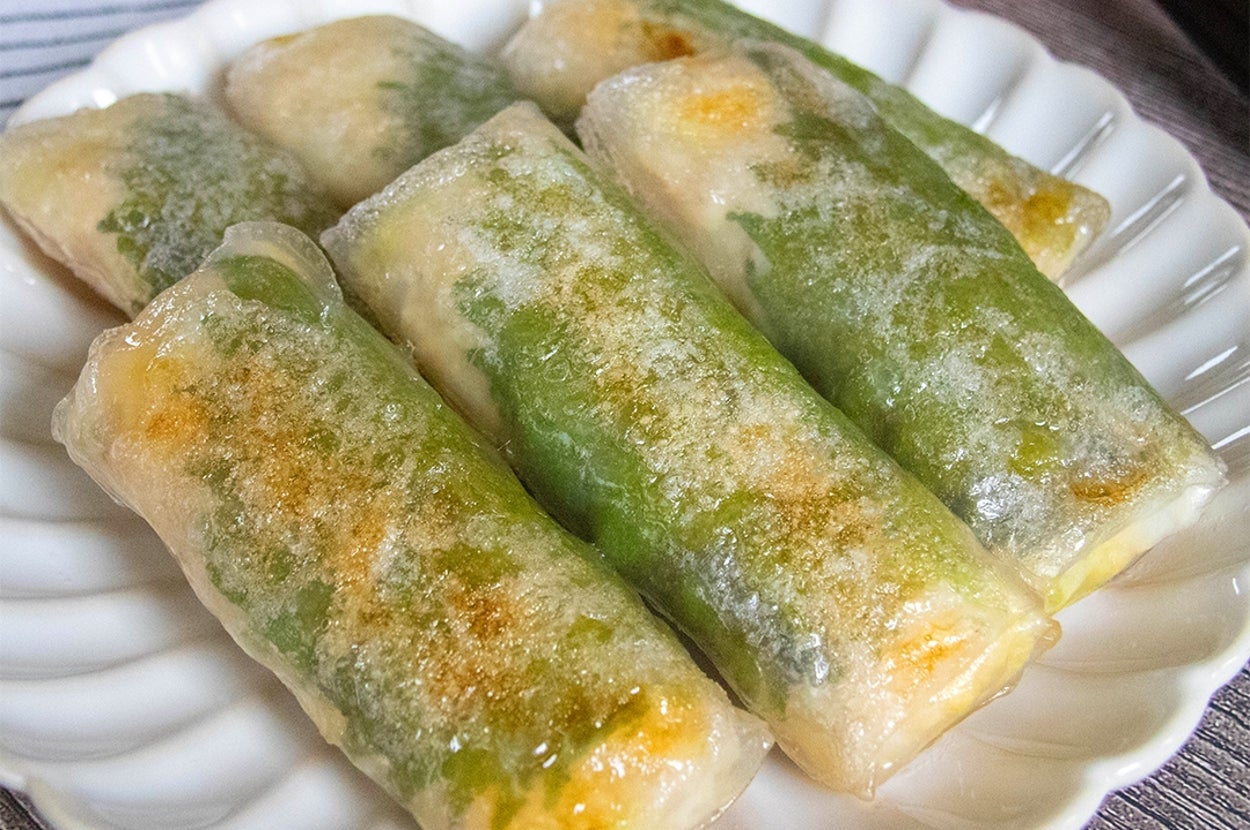 お皿に盛られた5個の春巻き、パリッとした生地の中に野菜やチーズが見える。隣にゴマが盛られた小皿がある。