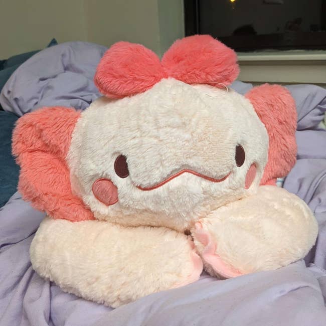 Cute plush artifact  with a smiling face, featuring ample  bows and rounded cheeks, sitting connected  a bed