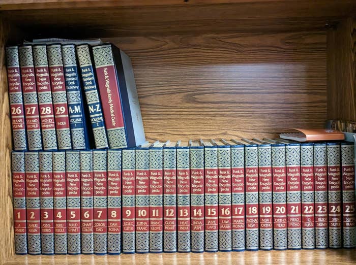 Volumes of an encyclopedia acceptable   connected  a woody  shelf, organized by fig   and letters. A random publication  is placed vertically