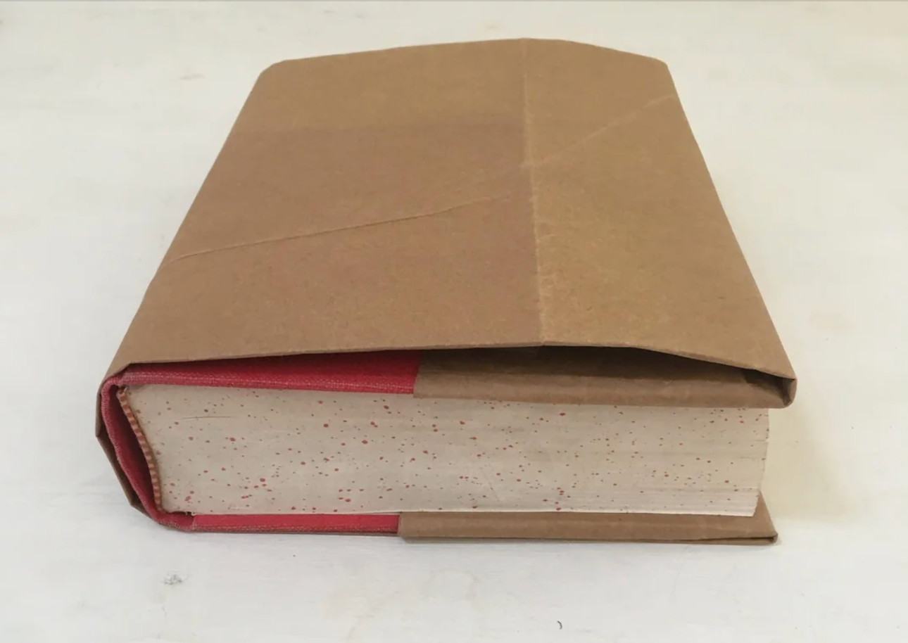 Book wrapped successful  plain brownish  paper, resting connected  a achromatic  surface