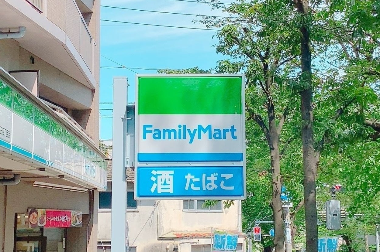 ファミリーマートの看板が建物の外にあり、近くには酒とたばこの文字が見えます。周囲には緑豊かな木々があります。