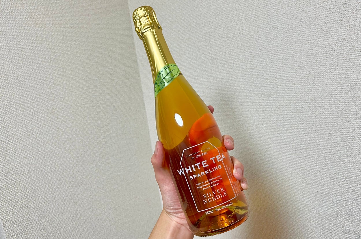 手に持たれた白茶スパークリングワインのボトル。ラベルには「WHITE TEA SPARKLING SILVER NEEDLE」と書かれています。