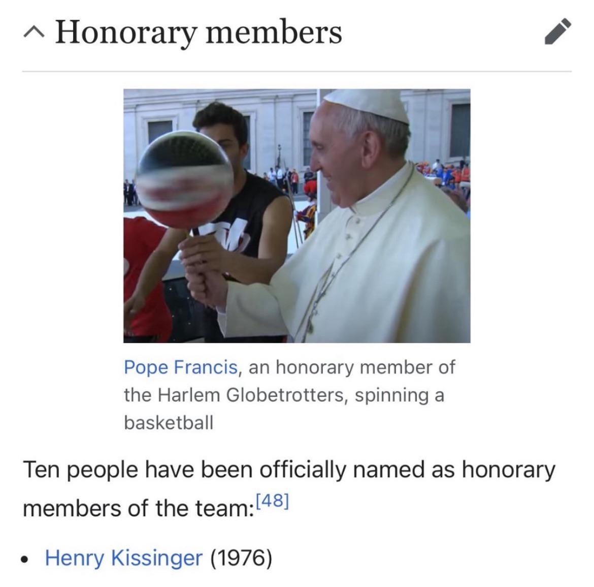 Pope Francis spins a basketball, indicating his honorary membership with the Harlem Globetrotters
