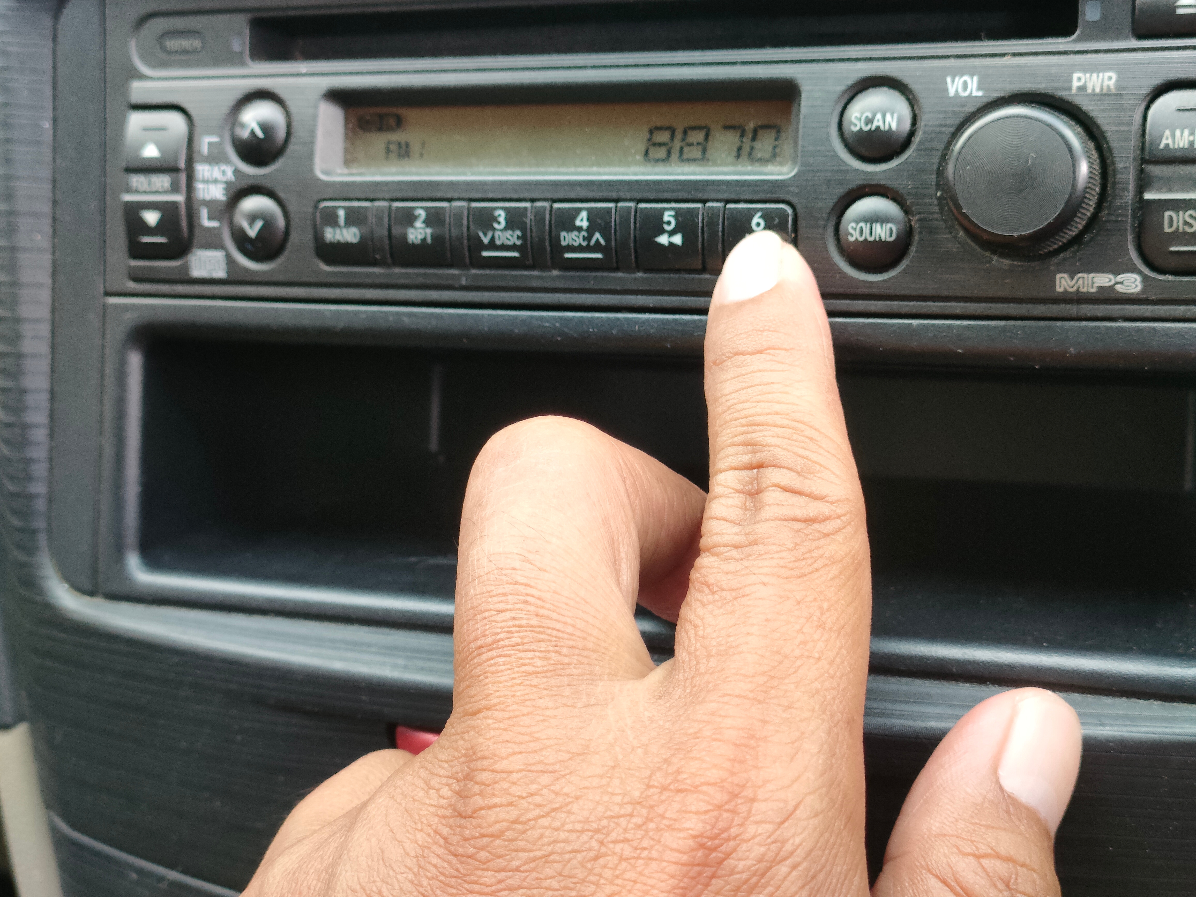 Håndinnstiller en bilradio til FM 88.7-frekvens