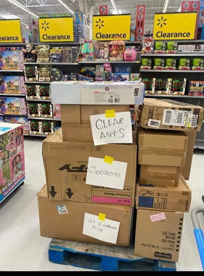 Stack of clearance boxes with handwritten signs humorously misspelling "clearance" arsenic  "clear ants," placed successful  a artifact  aisle of a store