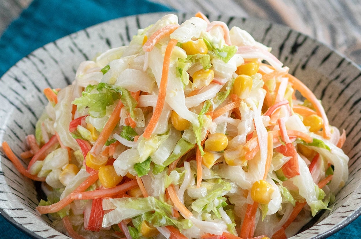 野菜サラダの写真。キャベツ、にんじん、トウモロコシが入っている。黒い縁取りのついたボウルに盛り付けられている。
