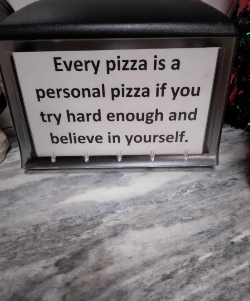 Sign on a stand reads: "Every pizza is a personal pizza if you try hard enough and believe in yourself."