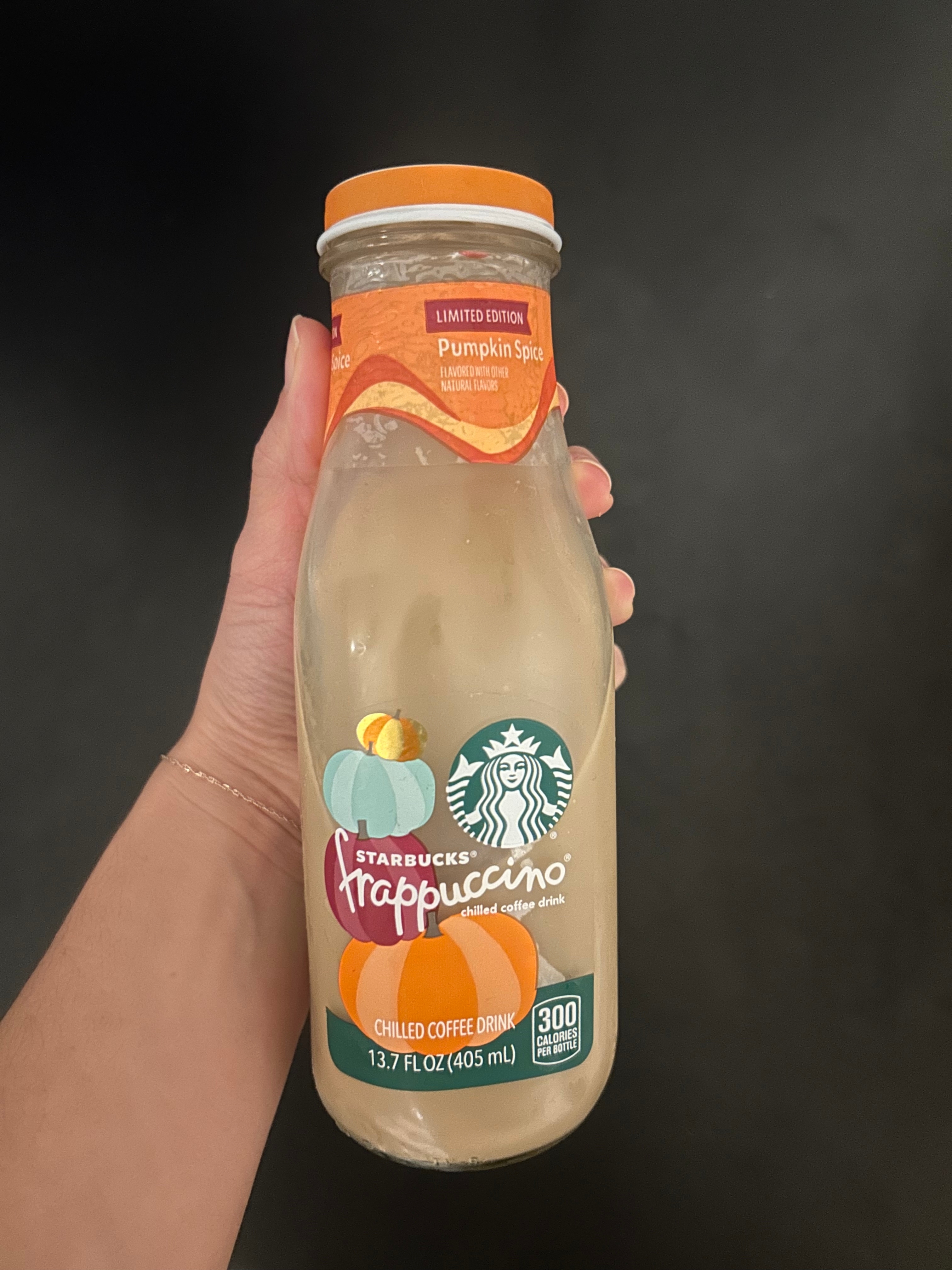 A hand holds a Starbucks Frappuccino bottle, limited edition pumpkin spice flavor, with 300 calories label