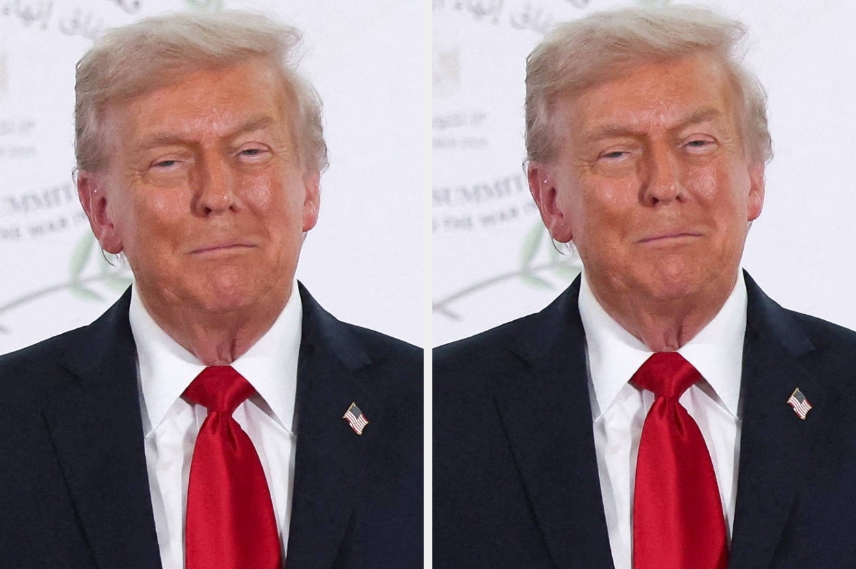 A man in a suit and red tie stands against a backdrop featuring indistinct logos and text