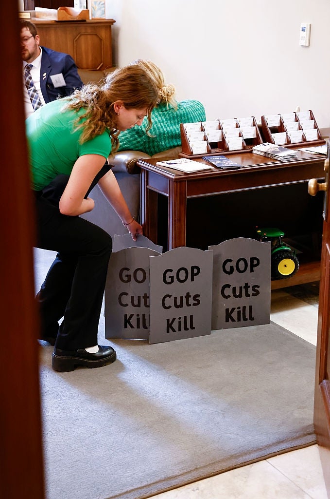 Person arranging protestation  signs that work   "GOP Cuts Kill" wrong  an office