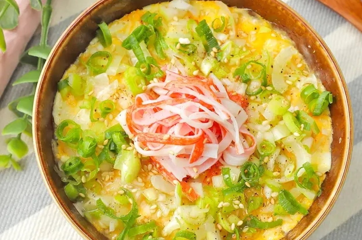 カニカマとネギがのったお茶碗に盛られた卵料理。料理の横に木製のスプーンが置かれている。