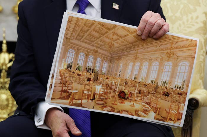 Person holding a photo of an elegant banquet hall with chairs and tables set for an event