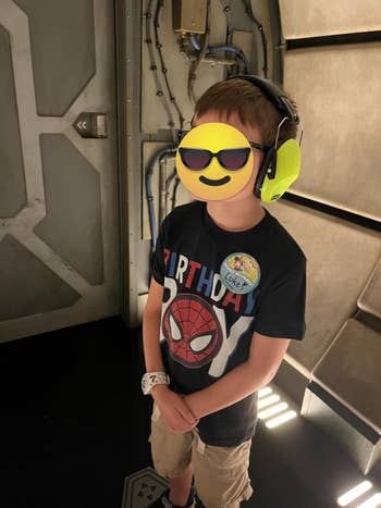 Child wearing noise-canceling headphones, Spider-Man shirt, and 