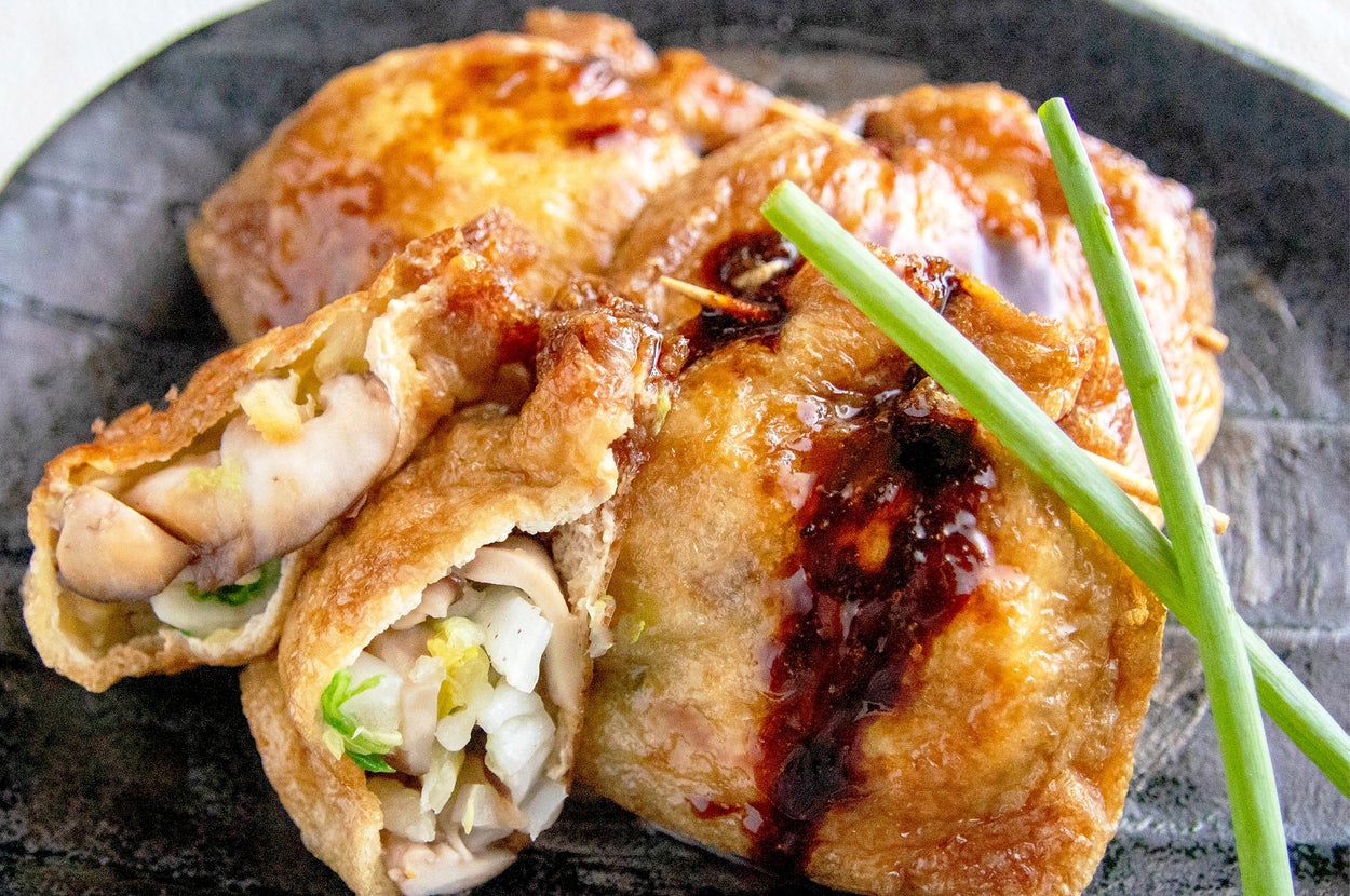 皿に盛られた料理。揚げた袋状の餃子の中に、野菜と肉が詰められている。ショウガが添えられている。