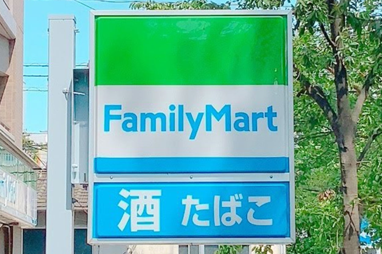 ファミリーマートの看板。上部に店舗名、下部に「酒 たばこ」と表示。道路のそばに設置。