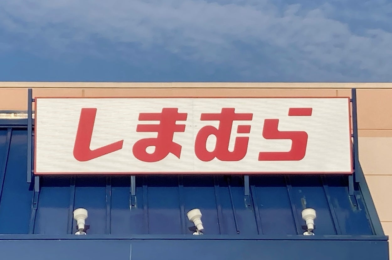 Sign with Japanese characters "しまむら" on a store facade, under a clear sky
