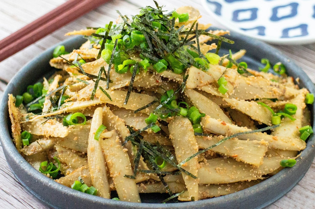 ゴボウサラダの盛り付け。薄切りゴボウが山盛りになり、刻み海苔とネギがトッピングされている。隣には箸が置かれている。