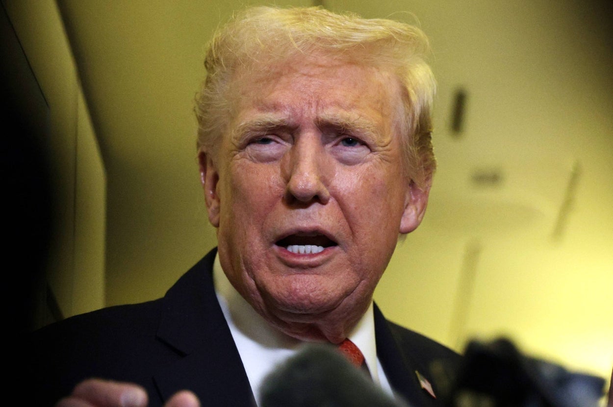 A person speaking at a public event, wearing a suit