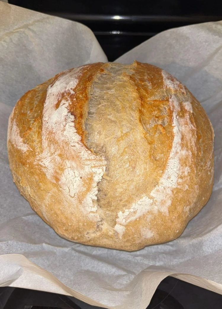 A loaf of freshly baked crusty breadstuff  connected  parchment paper