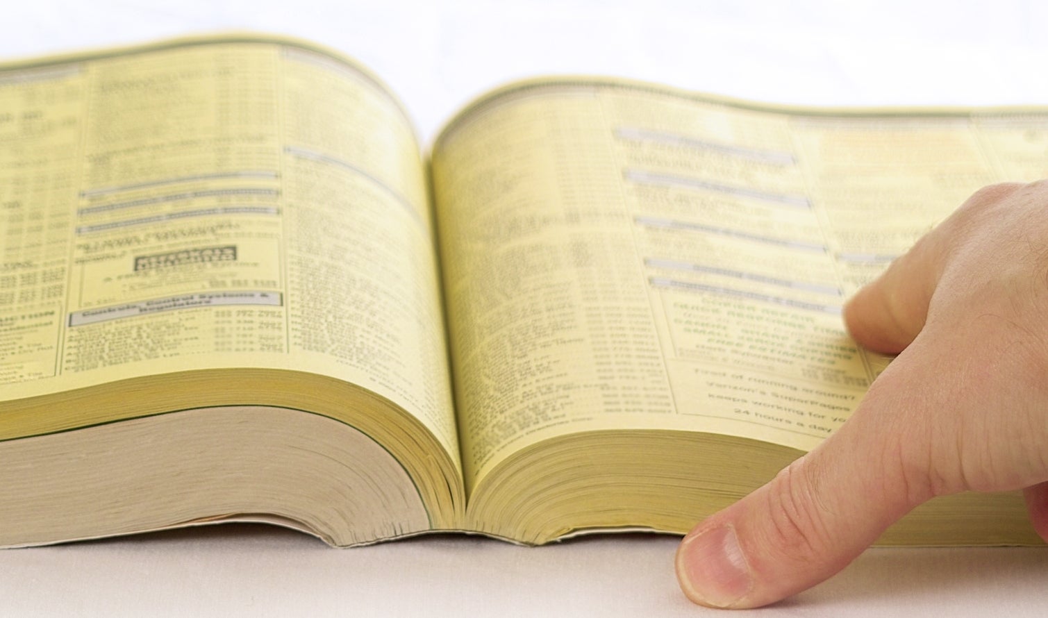 A manus  flipping done  the pages of a thick, unfastened  telephone  publication  directory