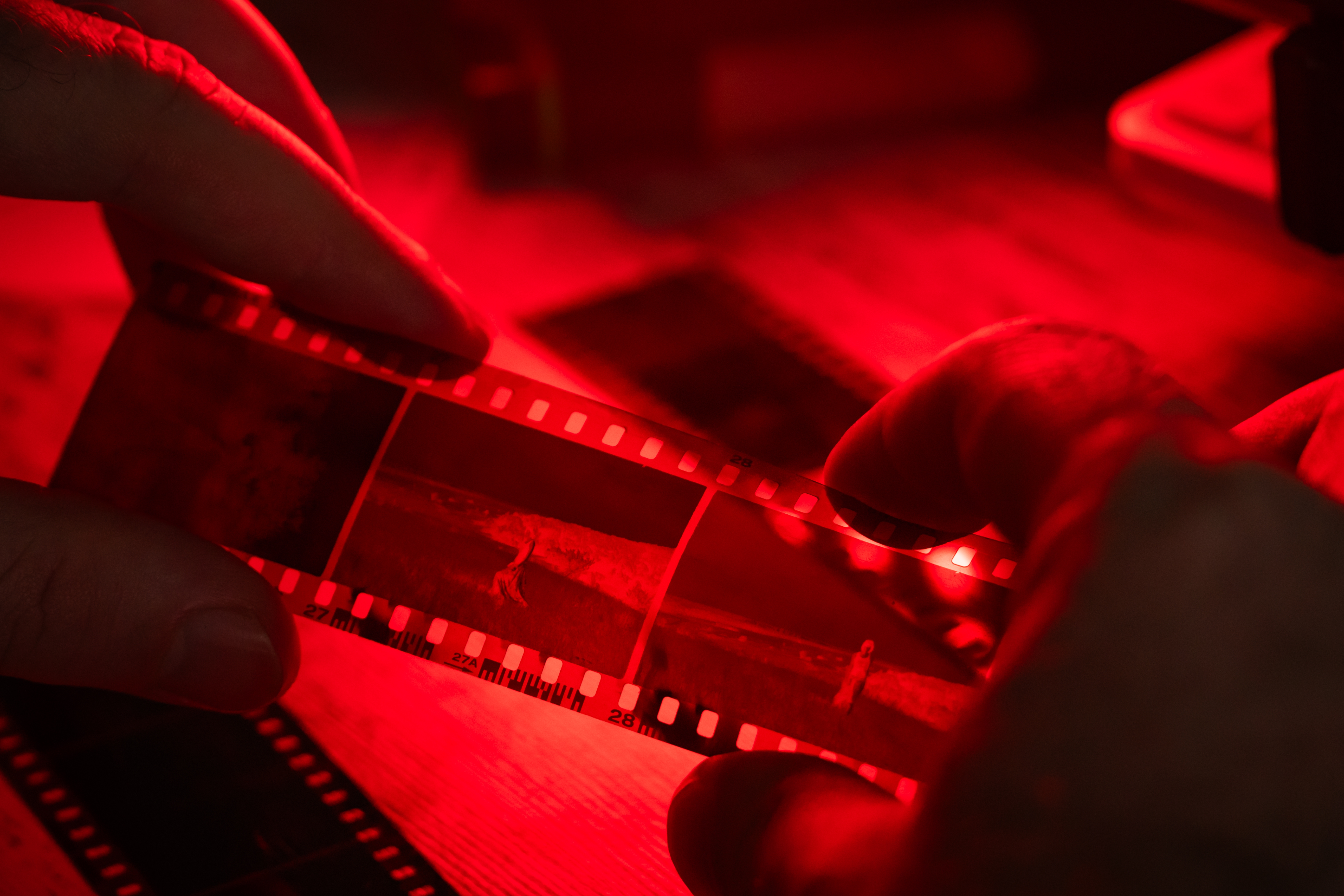 Hands holding photographic negatives nether  reddish  airy  successful  a darkroom setting