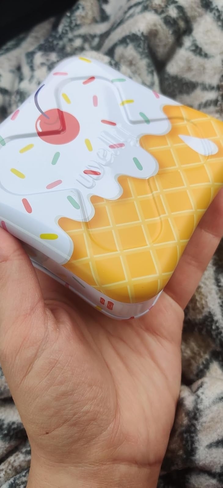 Hand holds a waffle-inspired tiny  instrumentality  with an crystal  pick  plan  connected  the lid, featuring a cherry and colorful sprinkles