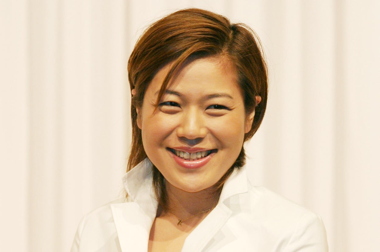 スーツを着た笑顔の女性がカメラに向かって立っている。