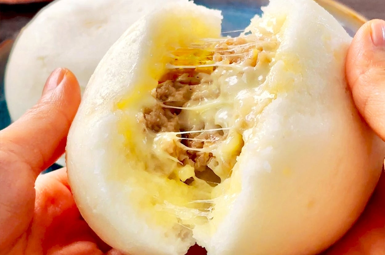中華まんを手で割り、チーズと肉の具が見える。