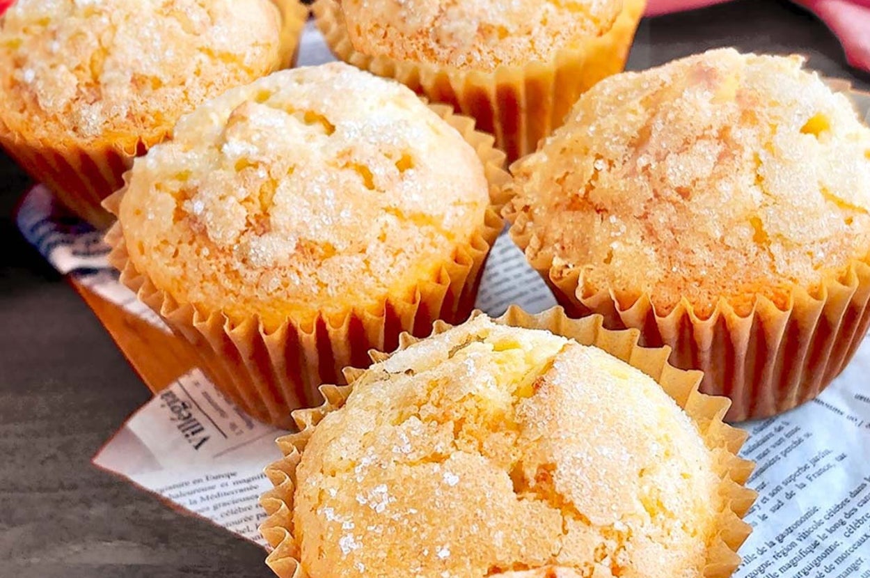 テーブルに並べられた5つの砂糖がけマフィン。背景にピンクの布がある。